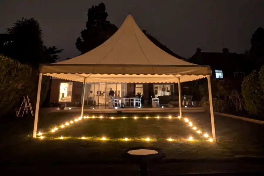 A pagoda marquee lit with candles at night