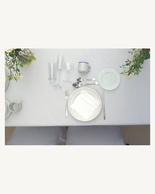 A place setting from our package: plate, napkin, cutlery, glassware and cup on white linen