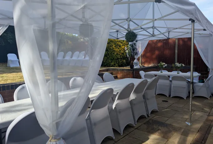 Covered chairs and laid tables under a dressed garden gazebo
