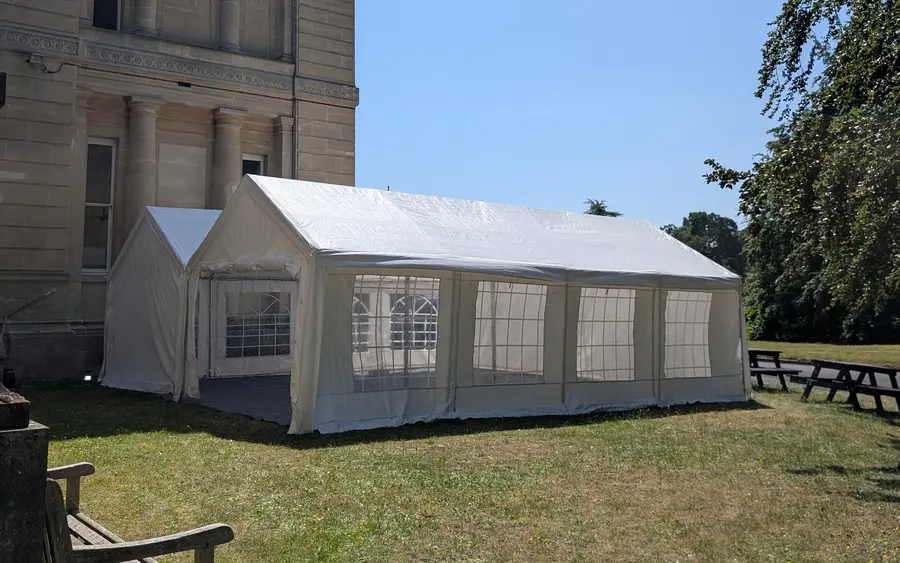 Linked marquees with window sides on a lawn outside a period building